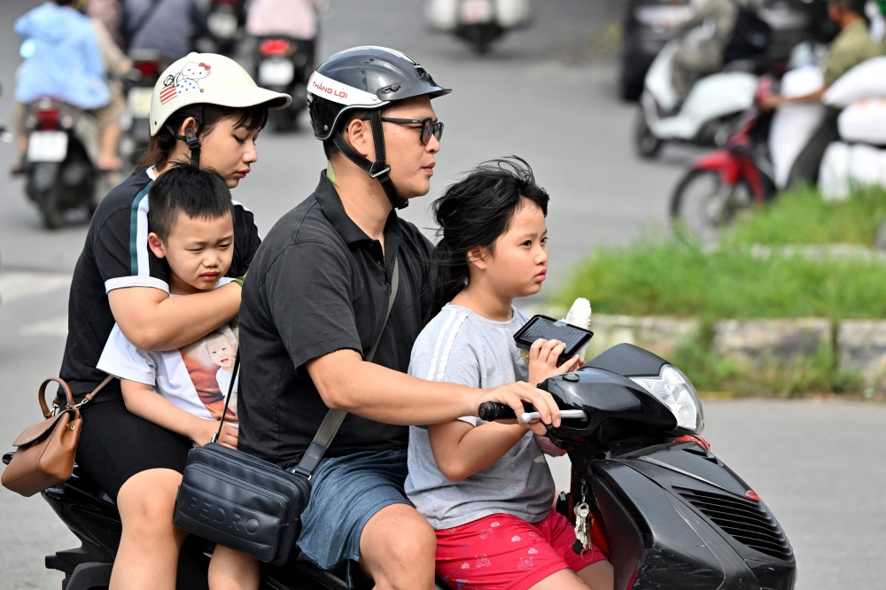 A family rides a motorcycle along a street in Hanoi on June 4, 2025. Vietnam has scrapped a long-standing policy of limiting families to two children, state media said on June 4, as the communist-run country contends with a declining birth rate. — AFP pic 