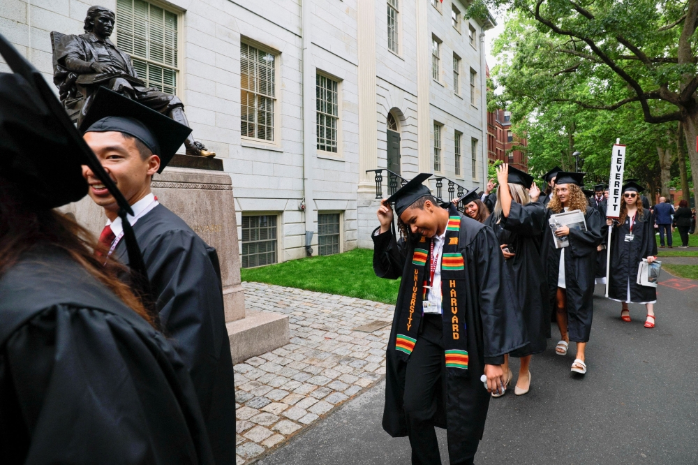 Students walk near the statue of John Harvard on the day of the 374th Commencement exercises at Harvard University in Cambridge, Massachusetts, May 29, 2025. US President Donald Trump on Wednesday suspended for an initial six months the entry into the United States of foreign nationals seeking to study or participate in exchange programmes at Harvard University, amid an escalating dispute with the Ivy League school. — Reuters pic 