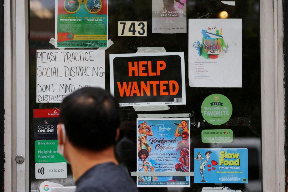 A pedestrian passes a ‘Help Wanted’ sign in the door of a hardware store in Cambridge, Massachusetts. US jobs growth slowed in May but remained steady with 139,000 new positions added amid ongoing trade tensions and tariff uncertainty. — Reuters pic