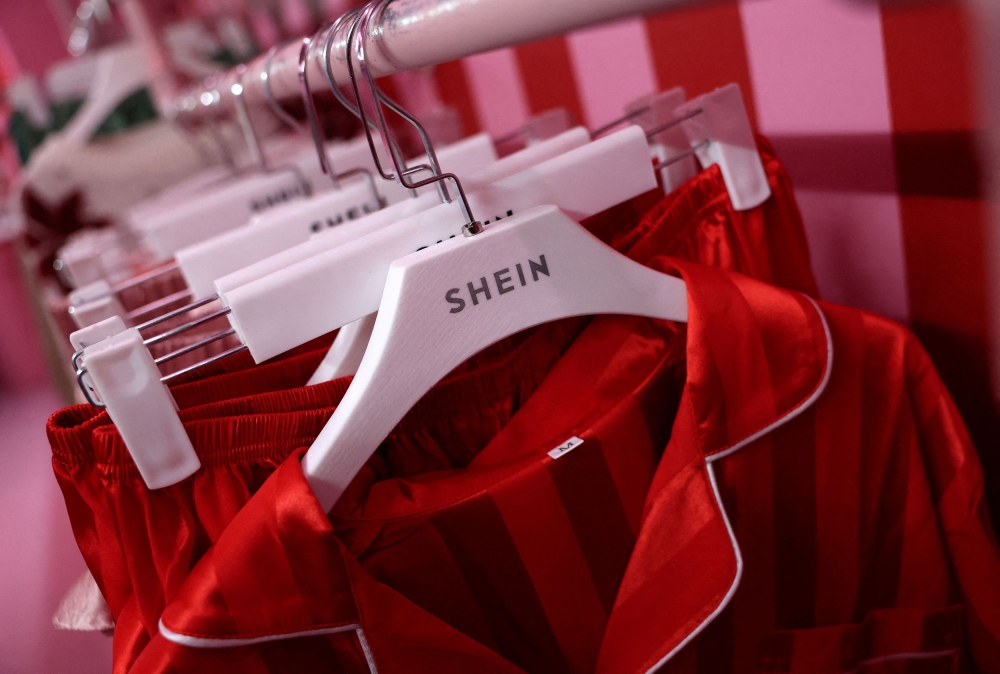 A company logo for fashion brand Shein is seen on a rail of clothing on its Christmas bus as part of a nationwide promotional tour in Liverpool, Britain, December 14, 2024. Much of Shein’s production takes place in the so-called ‘Shein village’ in Guangzhou, China, where workers often sew for 12–14 hours a day under poor conditions to keep pace with the demand for new items. — Reuters pic 