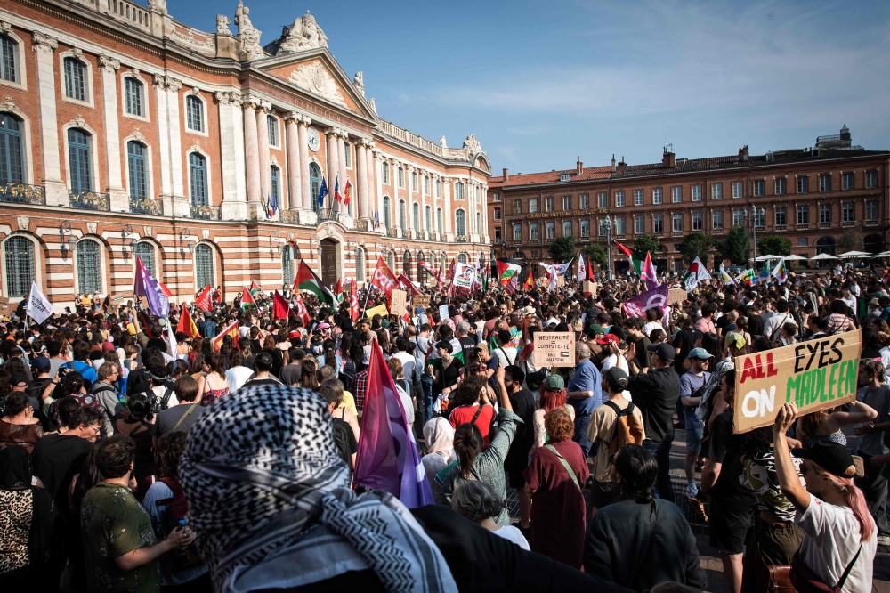 Protesters hold signs reading ‘Neutrality = complicity’ and Palestinian flags as they attend a demonstration to show their support for activists aboard a boat stopped by Israeli forces enroute to deliver aid to Gaza, in Toulouse, south-western France on June 9, 2025. — AFP pic 