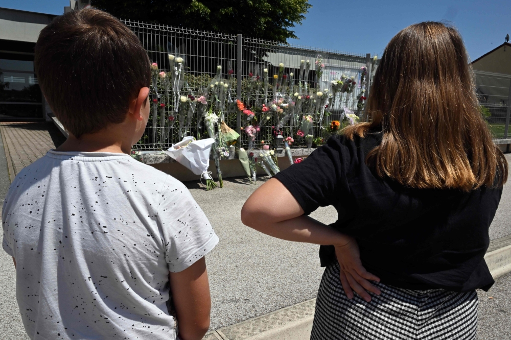 Pupils stand in front of flowers on the fence of Francoise Dolto middle school in Nogent yesterday. — AFP pic