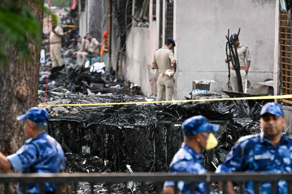 Police stand guard near wreckage at the site after Air India flight 171 crashed in a residential area near the airport in Ahmedabad today. — AFP pic