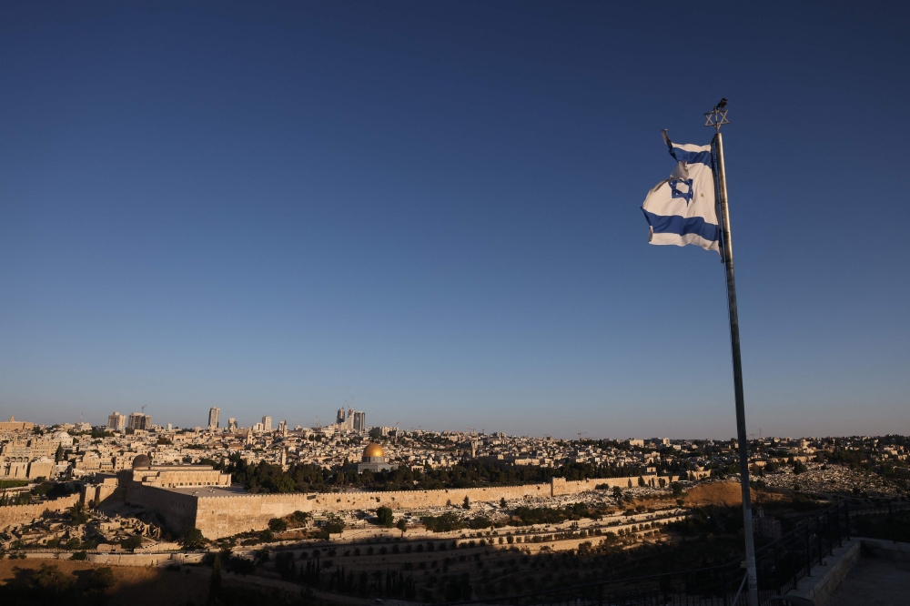 An Israeli flag flutters on the Mount of Olives as the sun rises over Jerusalem and its landmark Dome of the Rock mosque on June 13, 2025, following Israeli Prime Minister Benjamin Netanyahu’s announcement that a military operation was launched against Iran and would “continue for as many days as it takes”. — AFP pic 
