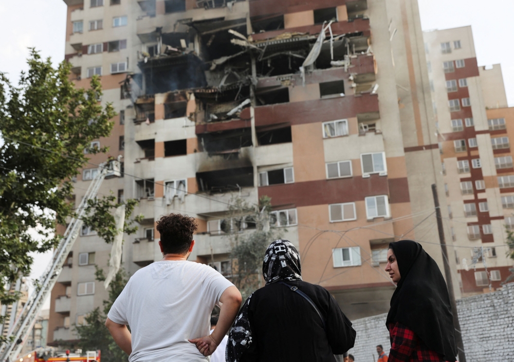 People look at a damaged building in the aftermath of Israeli strikes, in Tehran, Iran, June 13, 2025. — Majid Asgaripour/WANA (West Asia News Agency) handout pic via Reuters 