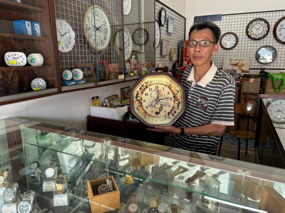 Kwan Siew Mung, 57, showing one of the old analog wall clocks that he recently repaired when Malay Mail visited his shop at Jalan Market, Ipoh. — Pictures by John Bunyan