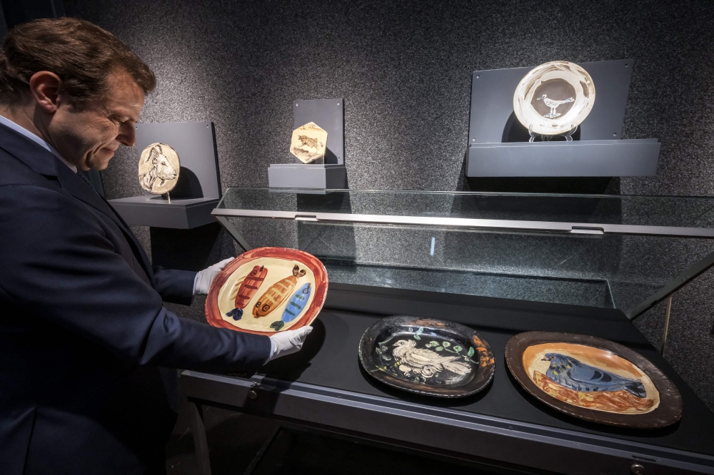 This photograph taken on June 5, 2025 shows the founder of Piguet auction house Bernard Piguet holding the terracotta dish ‘Three Fish’ (circa 1952) by Spanish painter, sculptor, printmaker, ceramicist, and theatre designer Pablo Picasso. — AFP pic