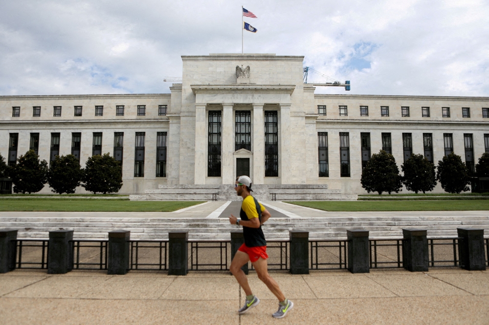 A jogger runs past the Federal Reserve building in Washington, DC August 22, 2018. The US central bank is expected to keep interest rates unchanged for a fourth straight policy meeting this week, despite President Donald Trump’s push for rate cuts, as officials contend with uncertainty sparked by the Republican’s tariffs. — Reuters pic