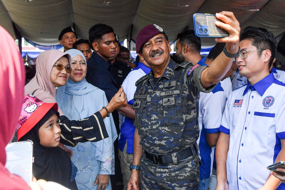 Outgoing Inspector-General of Police Tan Sri Razarudin Husain (centre) takes a selfie with residents of Kampung Parit Seberang at the Tasawwuf Studies Institute Complex in Negeri Sembilan on June 15, 2025. — Bernama pic
