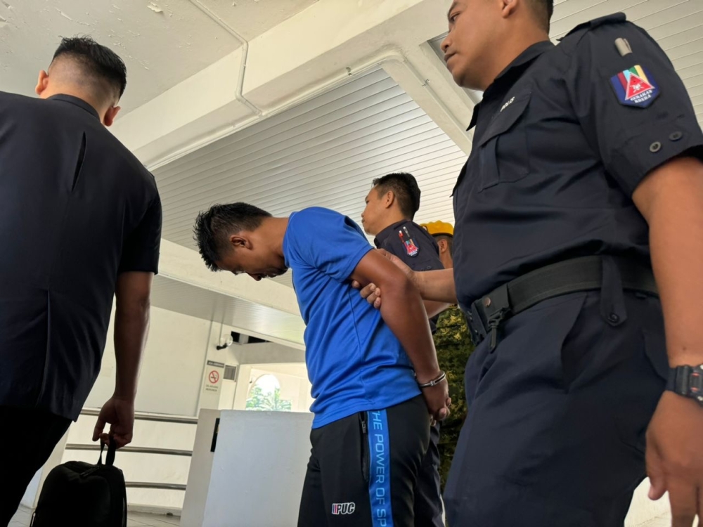 The accused, Meor Azizi Zolkfle, being escorted out of the courtroom by policemen. He was earlier charged at the Kota Tinggi Sessions Court today on four counts of sexual assault. — Picture by Ben Tan