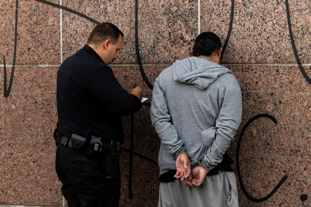 Los Angeles police (LAPD) officers arrest a man violating curfew near the Metropolitan Detention Center, as protests continue in response to federal immigration operations in Los Angeles on June 13, 2025. — File pic via AFP