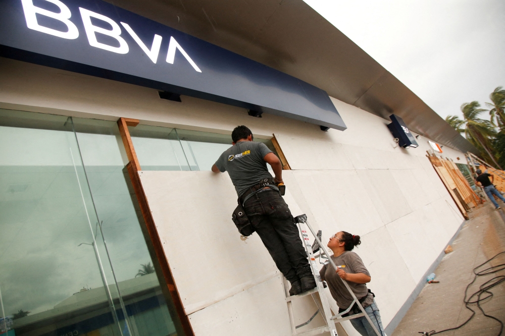 People board up a BBVA bank branch as Hurricane Erick strengthens off Mexico's Pacific Coast, in Puerto Escondido, Oaxaca state, Mexico, June 18, 2025. — Reuters pic  