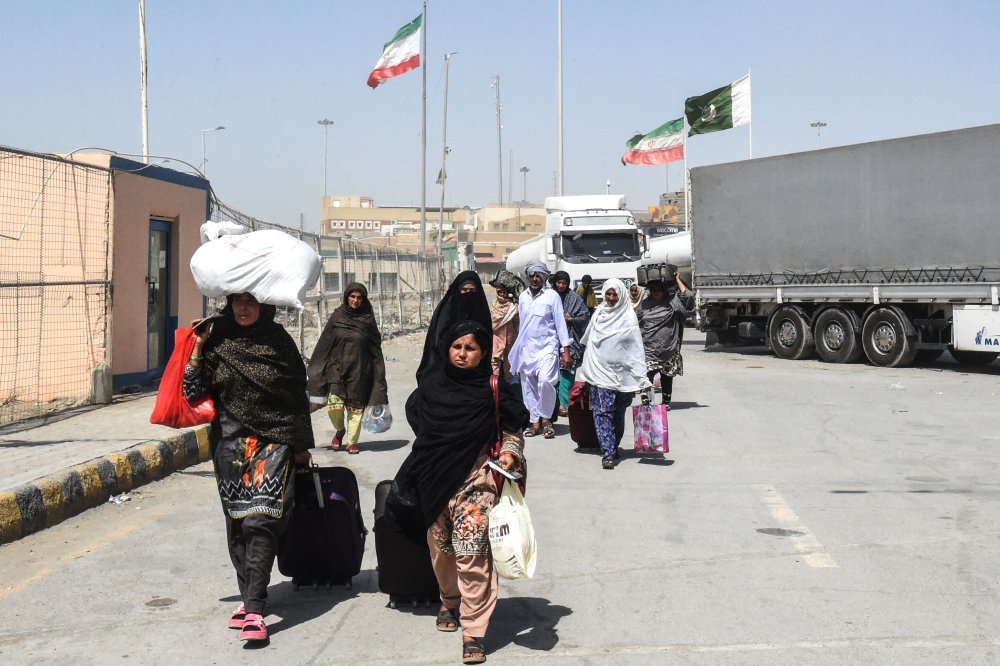 Pakistani Shiah pilgrims carrying their belongings walk across the Pakistan-Iran border after returning from Iran in Taftan, in Balochistan province, on June 19, 2025, amid the ongoing conflict between Israel and Iran. — AFP pic