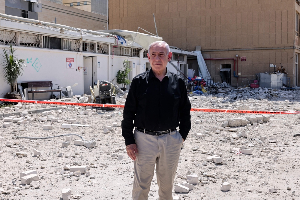 Israeli Prime Minister Benjamin Netanyahu stands amid debris outside the Soroka Hospital in the southern city of Beersheba, after it was hit by a missile fired from Iran on June 19, 2025. — AFP pic