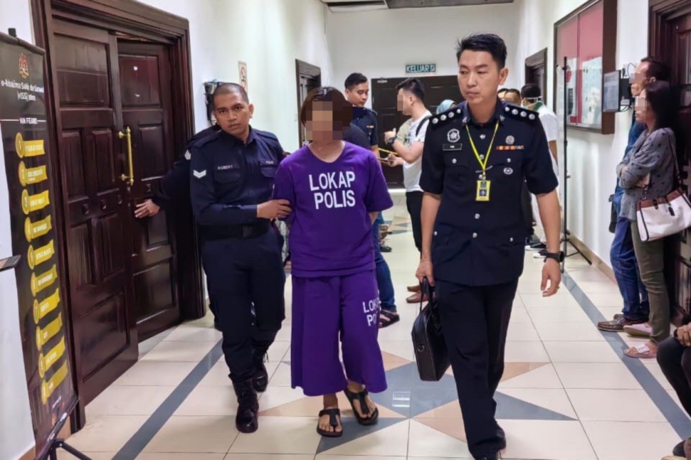 The suspect is escorted by police at the Kuching Court Complex. — Borneo Post pic