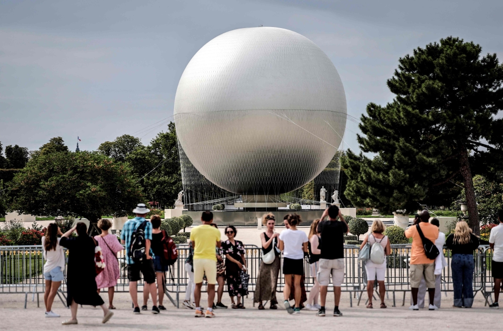 People look at the Paris 2024 Olympic Games cauldron, attached to a balloon in Jardin des Tuileries, in Paris on August 13, 2024. — AFP pic
