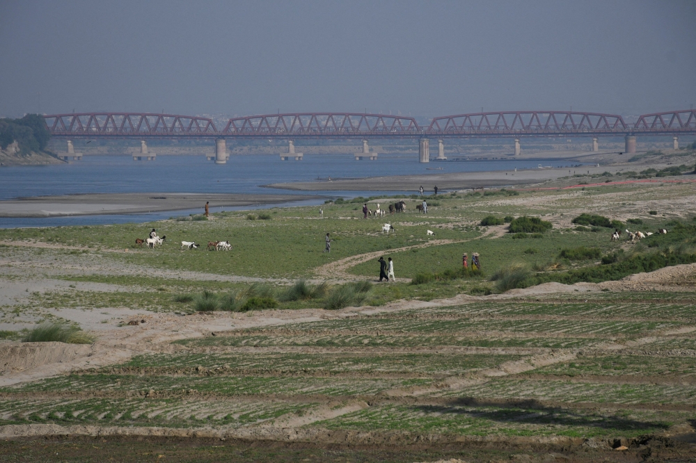 People walk next to a cultivated land on the dry riverbed of the Indus River in Hyderabad, Pakistan April 25, 2025. — Reuters pic