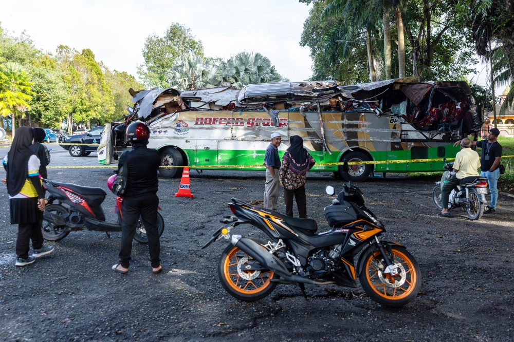 People look at the damaged chartered bus involved in the crash that killed 15 UPSI students, parked in front of the Gerik District Police Headquarters in Perak June 10, 2025. — Bernama pic