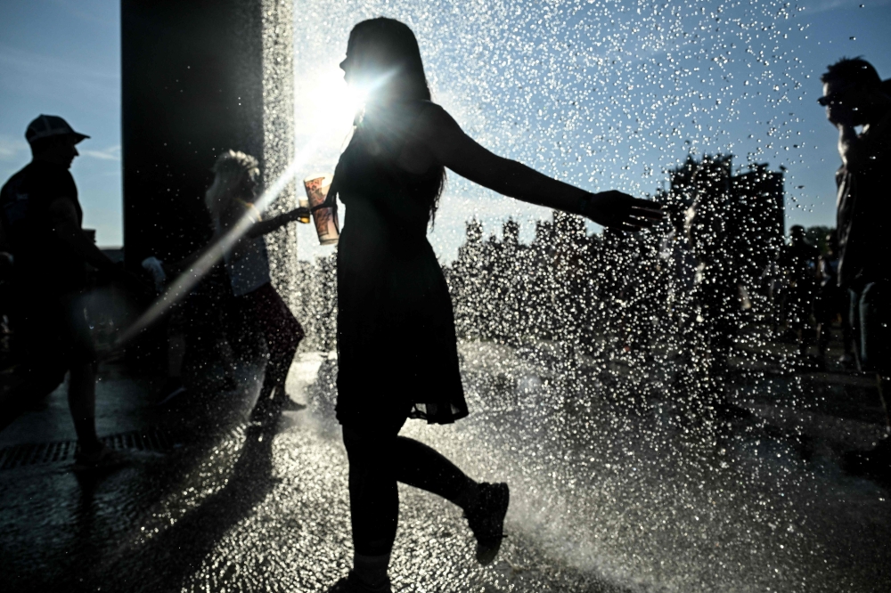 Heavy metal fans cool off under a curtain of water during the 18th edition of the Hellfest Summer Open Air rock and heavy metal festival in Clisson, western France June 19, 2025, as a heatwave hits France. — AFP pic 
