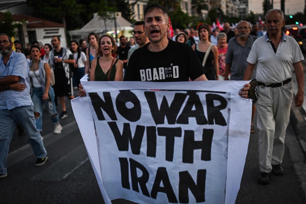 A protestor carries a placard as thousands march through central Athens towards the US embassy in support of the Palestinian people and against the US attacks in Iran, in Athens on June 23, 2025. — AFP pic