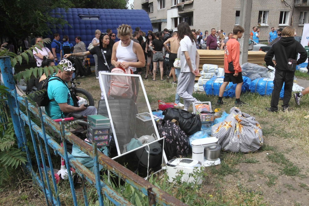 This handout photograph provided by the Dnipropetrovsk Regional Military Administration on June 24, 2025, shows local residents with their belongings gathered outside a damaged residential building following a missile strike in the Ukrainian city of Dnipro, amid the Russian invasion of Ukraine. — Dnipropetrovs’k Regional Military Administration handout pic via AFP 