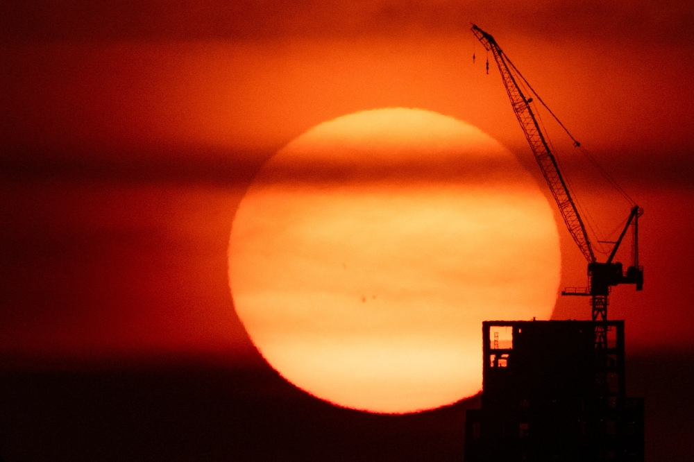 The sun sets behind a crane in Manhattan as an extreme heat warning is in effect in New York City June 23, 2025. — Reuters pic