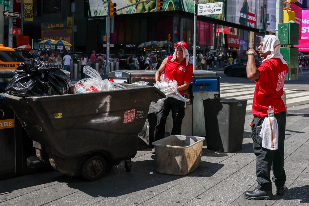 Workers with the Times Square Alliance wear cool towels as they empty trash cans during an extreme heat warning in New York City June 24, 2025. — Reuters pic