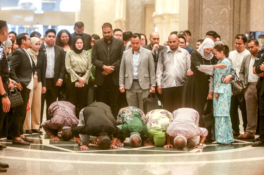 Muar MP Syed Saddiq Syed Abdul Rahman and his family members kneel in gratitude as they leave the courtroom following his acquittal on four charges of corruption and money laundering at the Palace of Justice, Putrajaya today. — Picture by Sayuti Zainudin