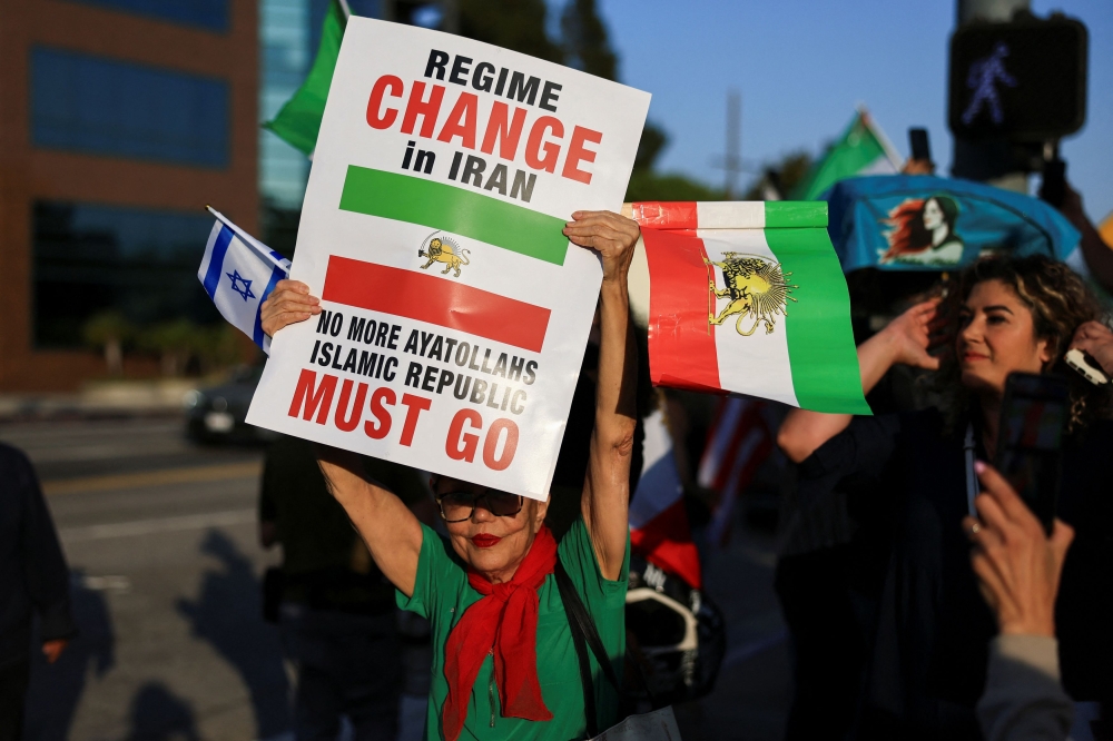 A demonstrator holding an Israeli flag and an Iranian flag from the reign of Shah Mohammed Reza Pahlavi takes part in a protest against the Iranian government outside the Federal Building in Los Angeles, California June 23, 2025. — Reuters pic