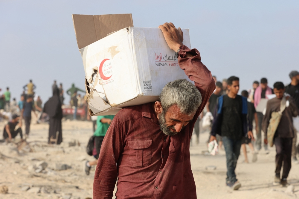 A man carries a box of aid along al-Rashid street in western Jabalia on June 22, 2025, after humanitarian aid trucks entered the northern Gaza Strip through the Israeli-controlled Zikim border crossing, amid the ongoing war between Israel and Hamas. — AFP pic