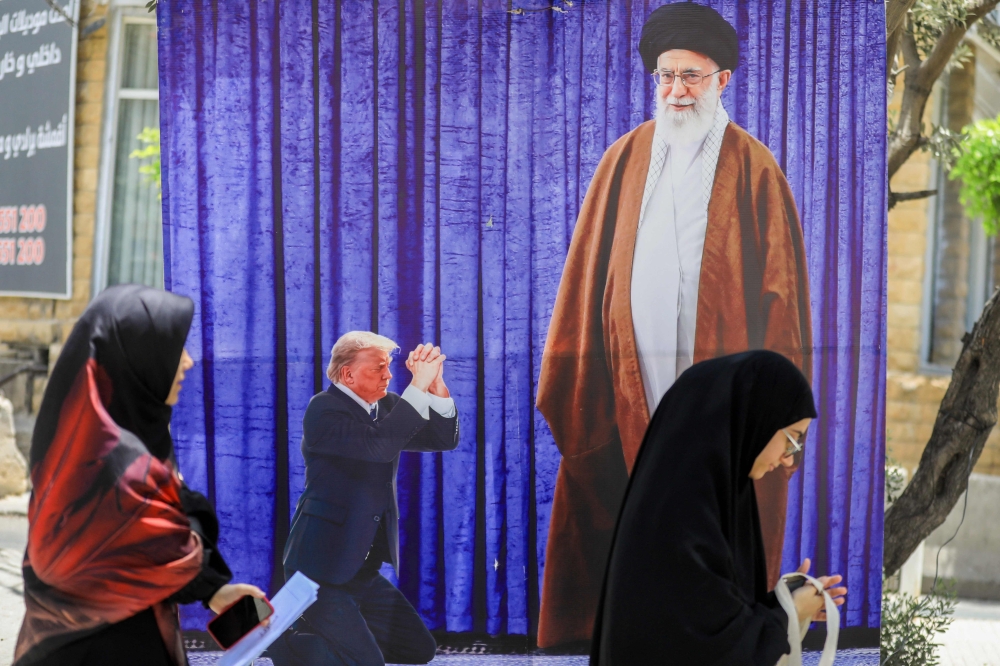 A poster depicting US President Donald Trump prostrating in font of Iran’s Ayatollah Ali Kamenei hangs in a southern Beirut suburb, on June 25, 2025. President Donald Trump insisted on June 25 that US strikes led to the ‘total obliteration’ of Iran’s nuclear capabilities and set the country’s atomic programme back ‘decades’, while Israel said it was still early to fully assess the damage. — AFP pic