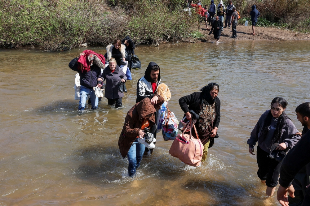 Alawite Syrians, who fled the violence in western Syria, walk in the water of the Nahr El Kabir River, after the reported mass killings of Alawite minority members, in Akkar, Lebanon March 11, 2025. Dozens of Alawite women and girls disappear this year in Syria. — Reuters pic  