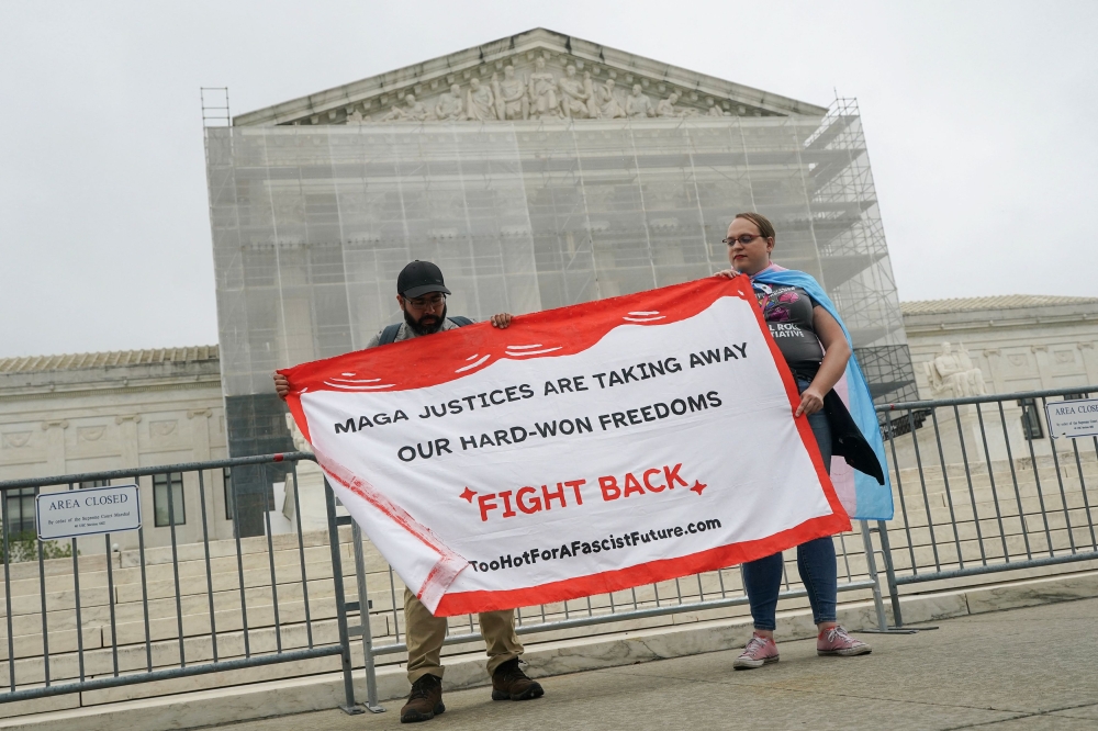 Demonstrators hold a banner reading “MAGA Justices are taking away out hard-won freedoms. Fight Back.” after the US Supreme Court dealt a blow to the power of federal judges by restricting their ability to grant broad legal relief in cases as the justices acted in a legal fight over President Donald Trump’s bid to limit birthright citizenship, outside the court in Washington, D.C. June 27, 2025. — Reuters pic  