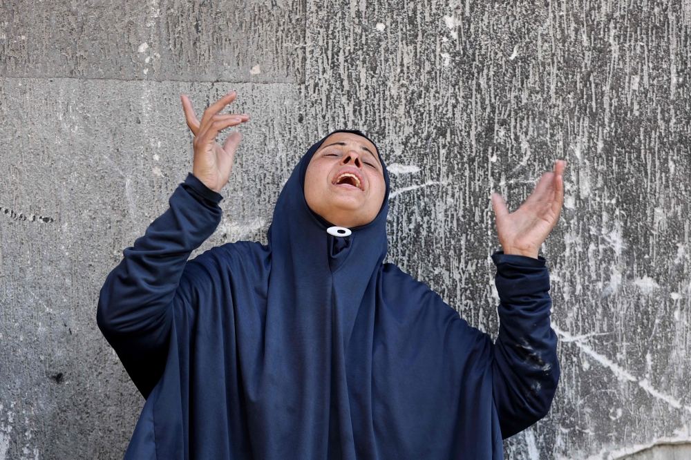 Palestinians mourn over the bodies of loved ones killed during overnight Israeli strikes, on the grounds of Al-Shifa hospital in the central Gaza Strip June 28, 2025. — AFP pic