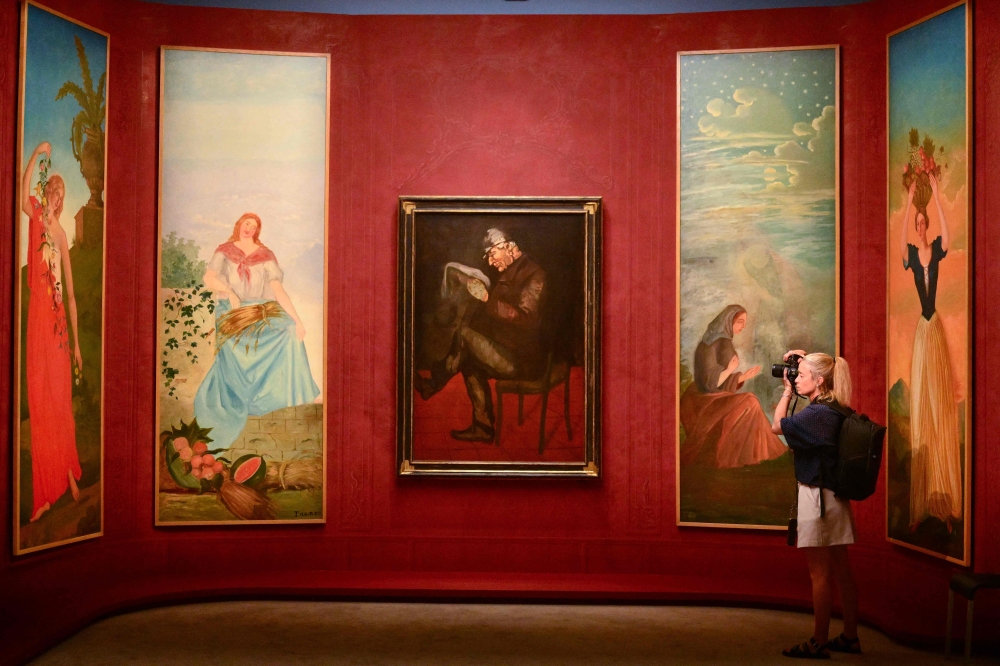 A woman takes pictures of paintings of French impressionist painter Paul Cezanne during a press preview of the ‘Cezanne au Jas de Bouffan’ (Cezanne at Jas de Bouffan) exhibition at the Granet Museum in Aix-en-Provence. — AFP pic