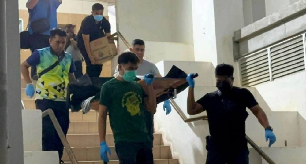 Police officers remove the bodies of a woman and a child from a flat in George Town July 1, 2025, after they were found in a decomposed state. — Picture via Facebook