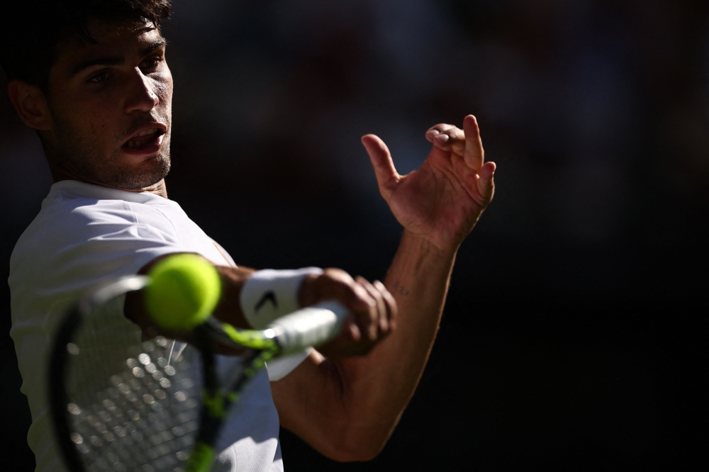 Spain’s Carlos Alcaraz plays a forehand return to Italy’s Fabio Fognini during their men’s singles first round tennis match on the first day of the 2025 Wimbledon Championships at The All England Lawn Tennis and Croquet Club in Wimbledon, south-west London, on June 30, 2025. — AFP pic