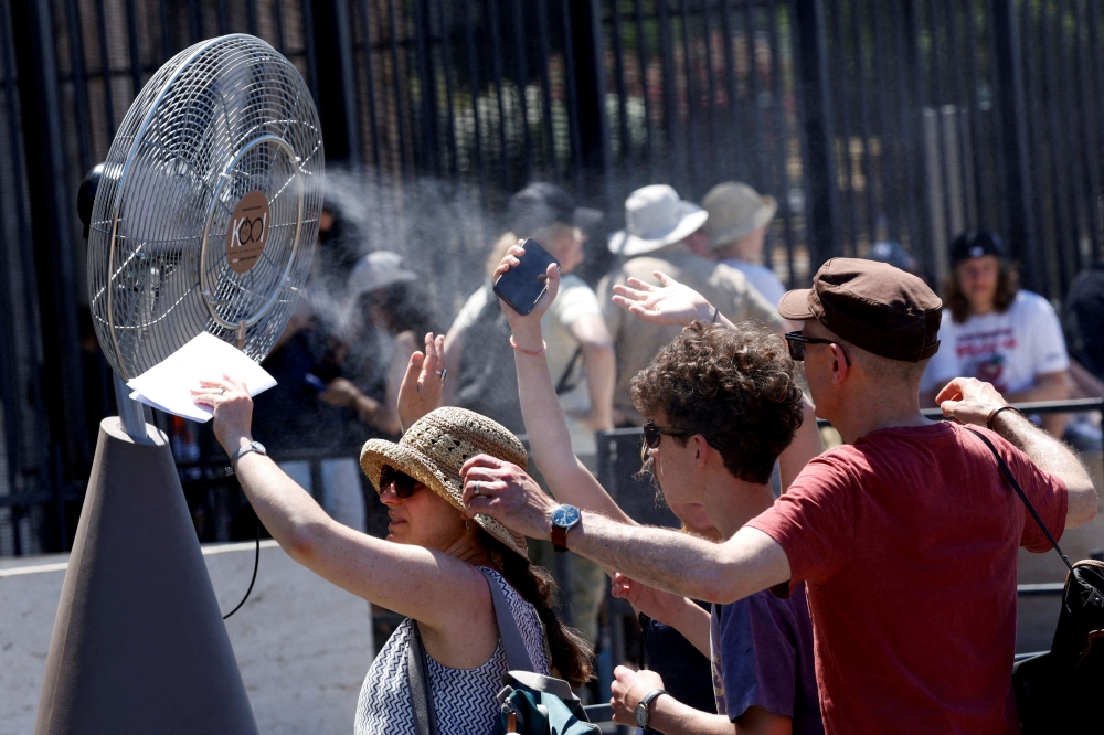 Tourists stand in front of a cooling fan installed outside the Colosseum in during the heatwave in Rome June 30, 2025. — Reuters pic