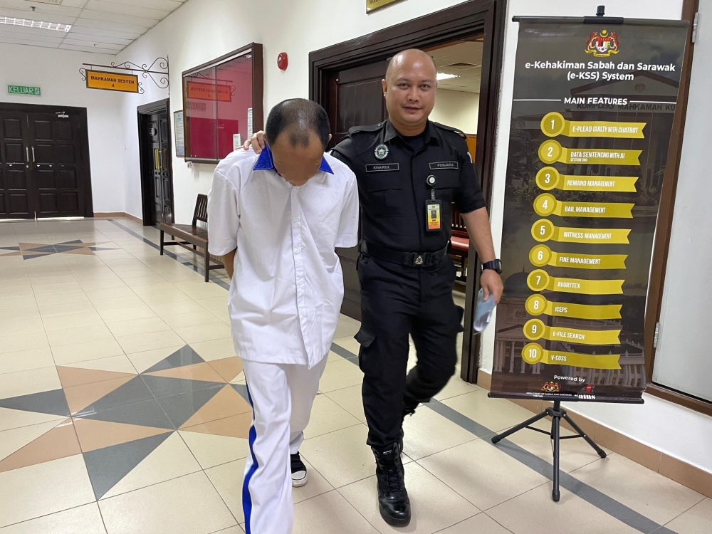 The accused (left) being escorted out of the courtroom after proceedings at the Kuching Court Complex. — The Borneo Post pic