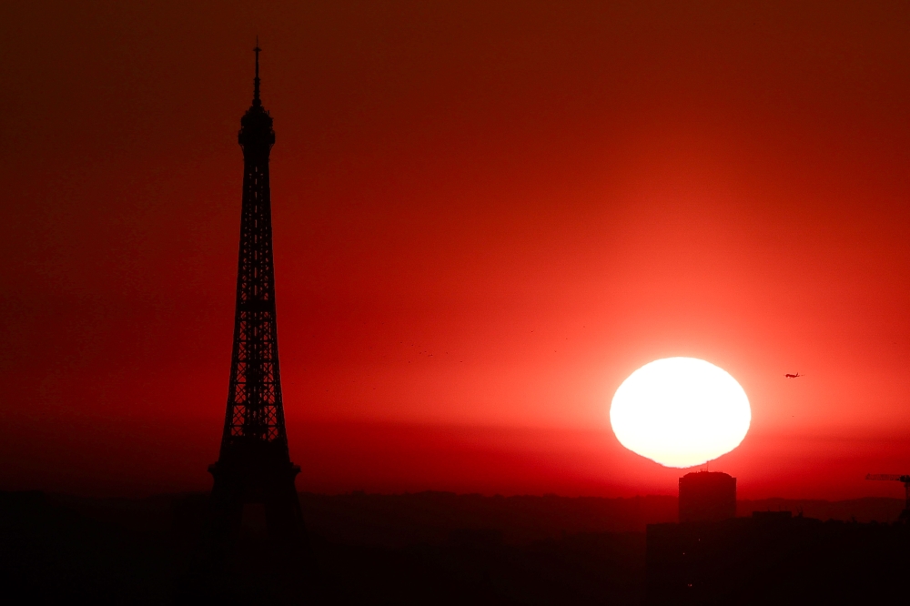 The sun rises by the Eiffel Tower in Paris on July 1, 2025, as the city is on red alert for high temperatures, with the top of the Eiffel Tower shut, polluting traffic banned and speed restrictions in place as a searing heatwave gripped Europe. — AFP pic 