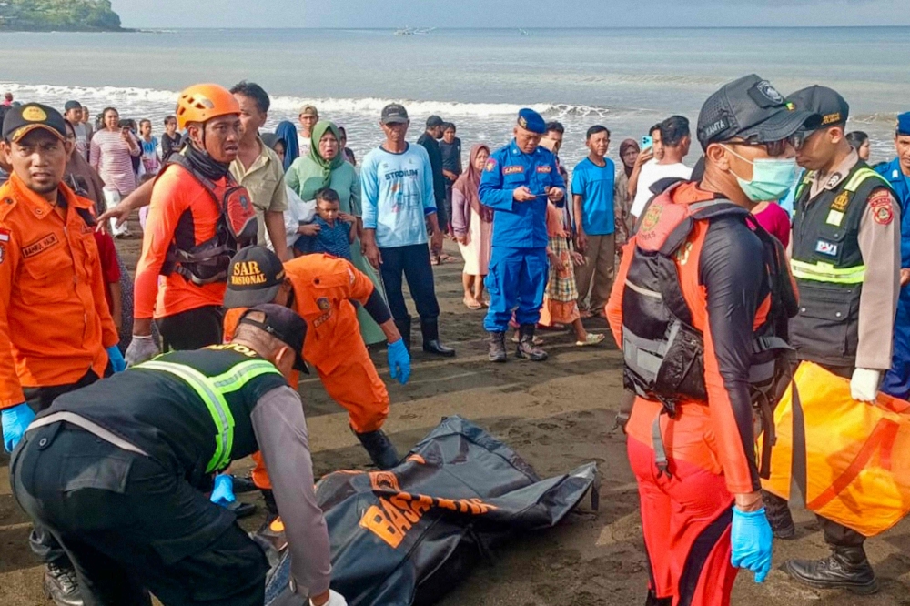 National Search and Rescue Agency (BASARNAS) shows a rescue team moving a victim's body brought to shore earlier by local fishermen after a ferry sank on its way to the resort island of Bali, in Banyuwangi, East Java. — AFP pic