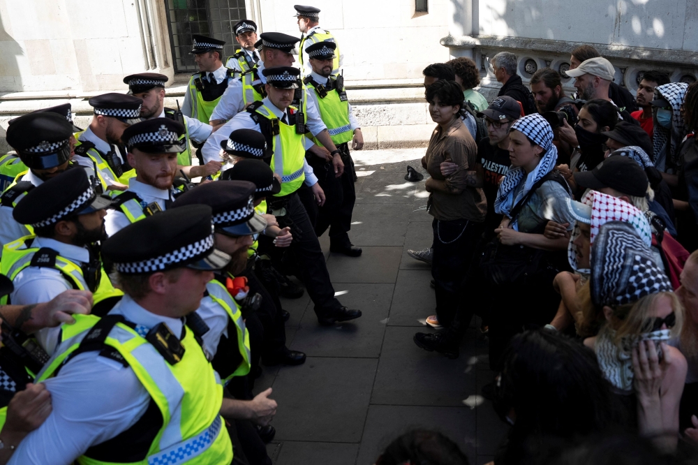 Supporters of the pro-Palestinian group Palestine Action scuffle with police officers outside the High Court in London July 4, 2025. — Reuters pic