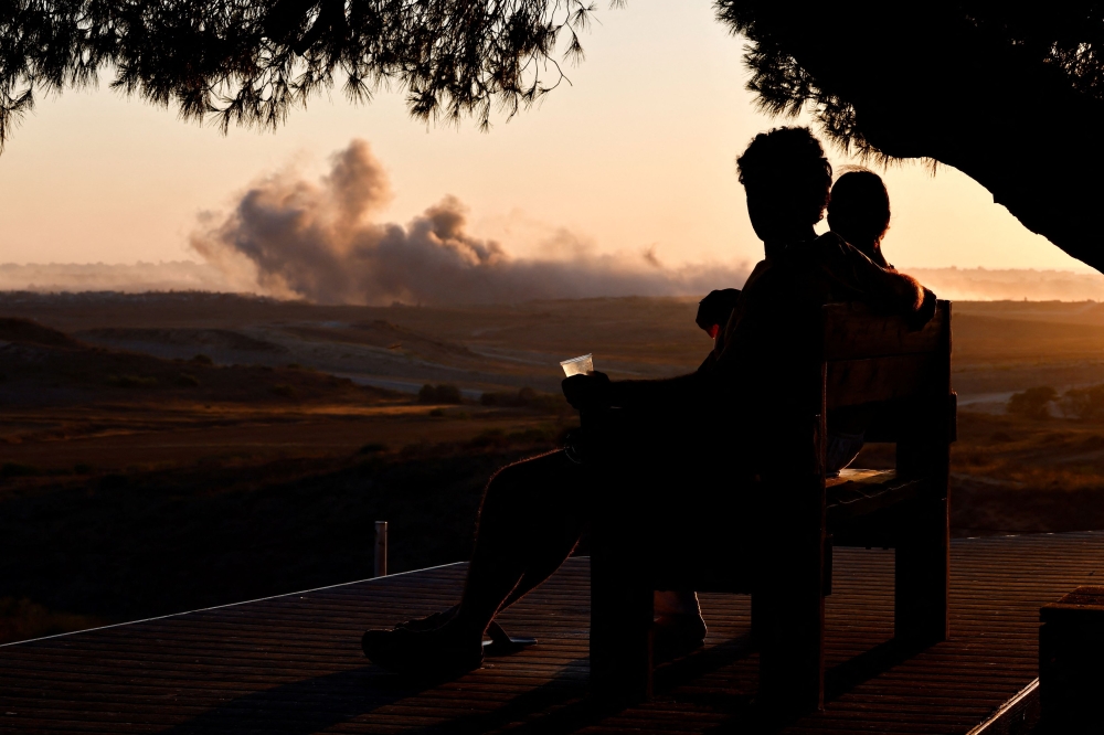 Israeli people look towards smoke rising in Gaza as they sit at a viewing point on the Israeli side of the border, July 5, 2025. — Reuters pic
