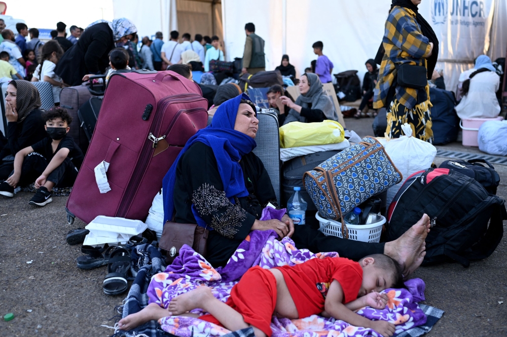 Afghan refugees rest with their belongings after arriving at the zero point of the Islam Qala border crossing between Afghanistan and Iran on June 28, 2025, following their deportation from Iran. — AFP pic