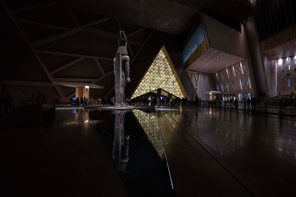 Visitors walk next the 3,200-year-old pink-granite colossal statue of King Ramses II at the entrance of the Grand Egyptian Museum (GEM), in Giza on the southwestern outskirts of the capital Cairo on February 7, 2025, set to open fully on July 3, following a partial opening in October. — AFP pic