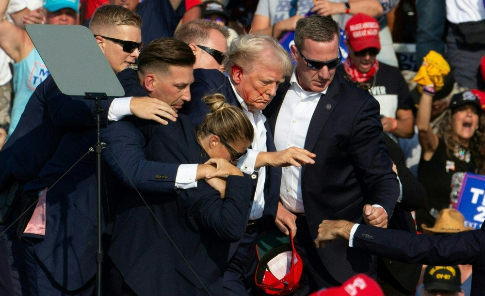 Donald Trump with blood on his face is surrounded by Secret Service agents as he leaves the stage at a campaign event at Butler Farm Show Inc. in Butler, Pennsylvania July 13, 2024. — AFP pic