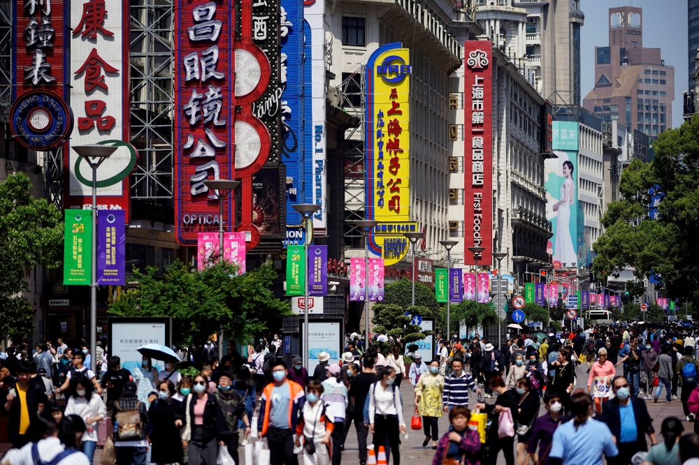 File picture of people walking along Nanjing Pedestrian Road in Shanghai. As China’s sluggish economy pushes local authorities to cut salaries and bonuses, one southern province has told officials they can pursue side jobs, saying it is OK to be a part-time driver, novelist or fitness coach. — Reuters pic