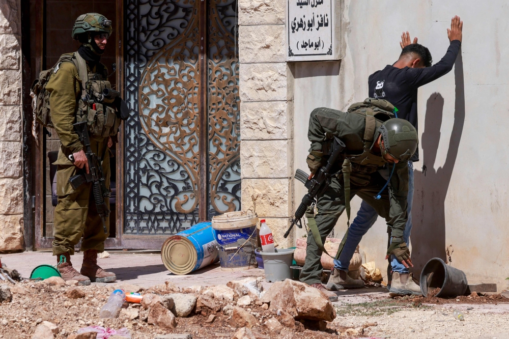 Israeli soldiers check a Palestinian man at the entrance of Tulkarem camp, in the occupied West Bank, during a military operation on July 6, 2025. — AFP pic