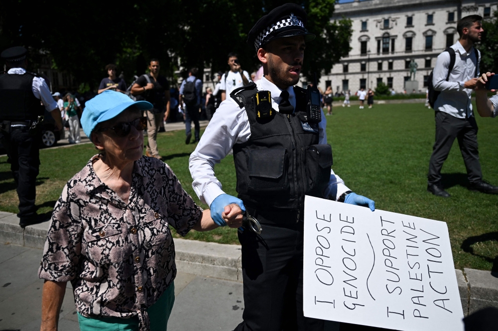 A Police officer holds a placard belonging to an arrested Protester as people gather in support of the pro-palestinian group 'Palestine Action', in Parliament Square, London on July 12, 2025. — AFP pic