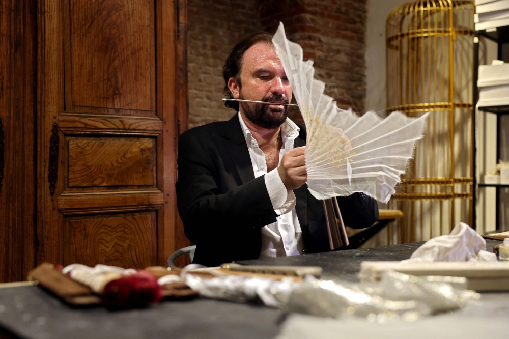French luxury hand fan designer Olivier Bernoux works on one of his fan creation in his store in Madrid, on July 4, 2025. — AFP pic